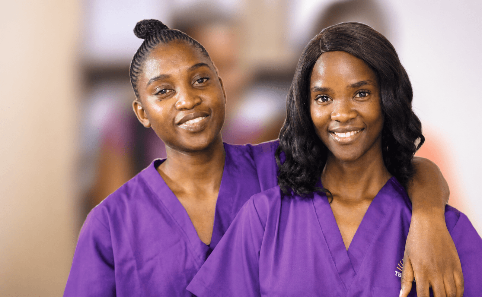 Two Tebelopele College healthcare students smiling in their purple uniforms
